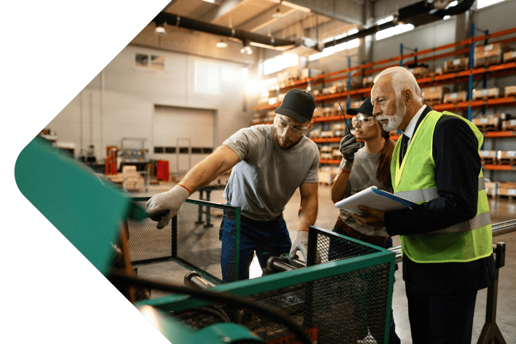 Two manufacturing staff showing a health and safety person a machine
